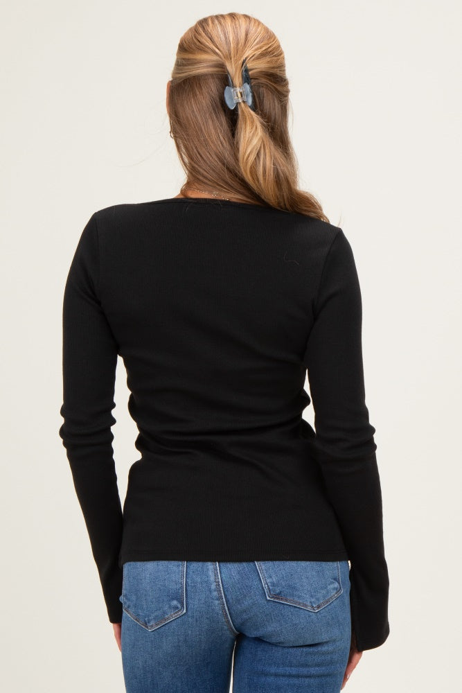 woman wearing a fitted black long sleeve top and blue jeans, seen from the back