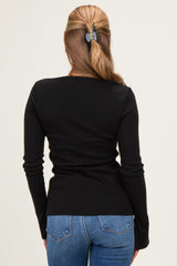 woman wearing a fitted black long sleeve top and blue jeans, seen from the back