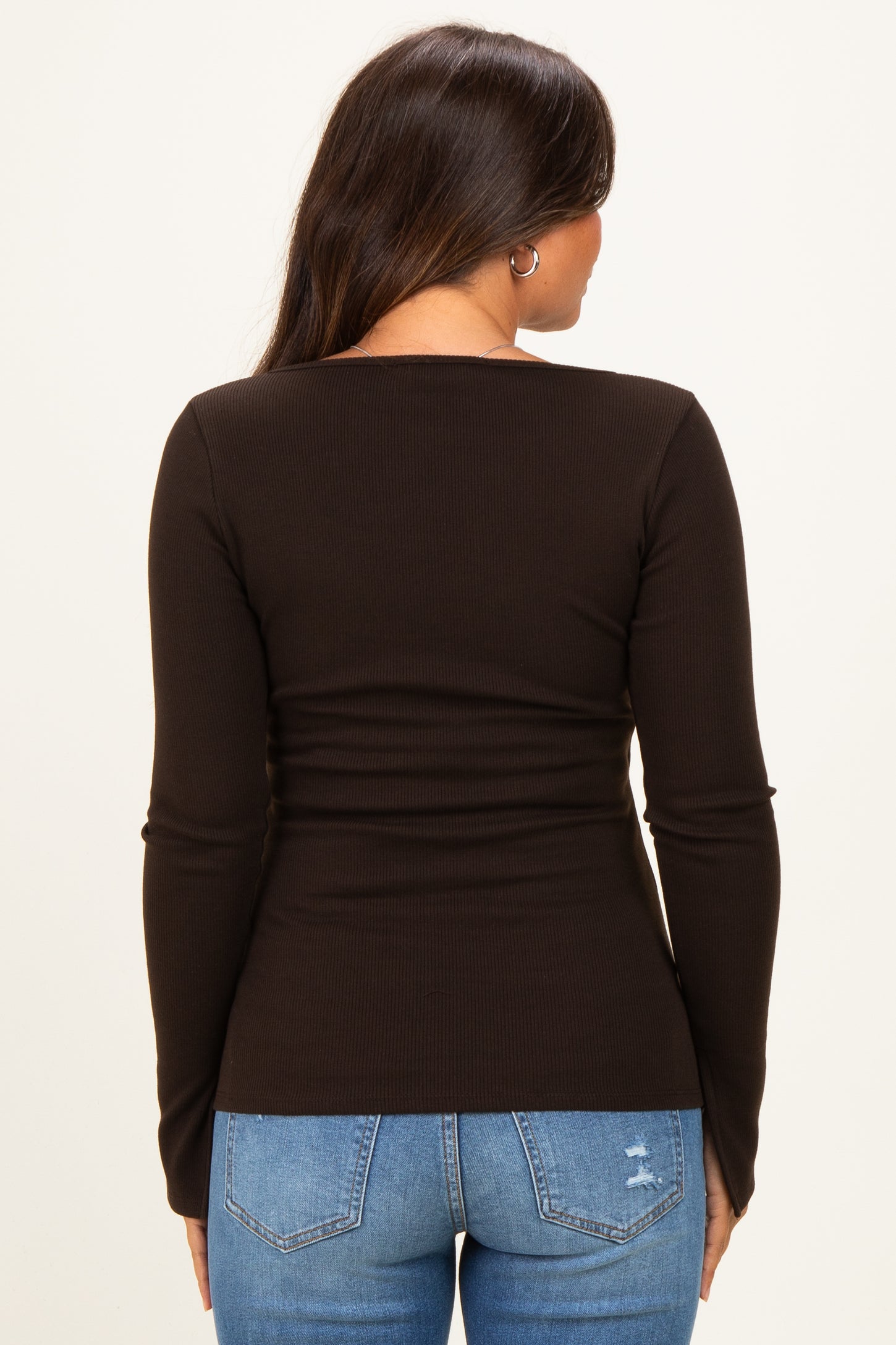 woman wearing a black long sleeve maternity top, showing the back view and paired with blue jeans