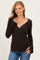 woman wearing a brown long sleeve wrap top with a v-neckline and bell sleeves, styled with blue jeans