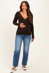 woman wearing a black long sleeve maternity top and distressed jeans, holding her baby bump