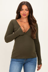 woman wearing a green maternity wrap top with long sleeves and a deep v-neckline, showcasing her baby bump