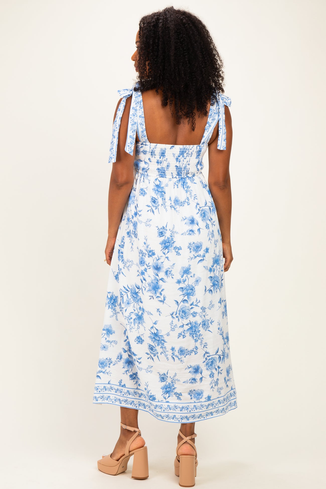 woman wearing a blue and white floral maxi dress with tie shoulder straps and a smocked back