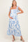 woman wearing a blue and white floral maternity dress with tie straps and holding her baby bump