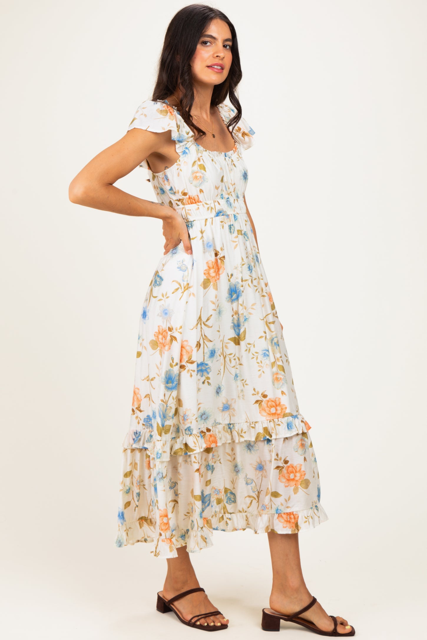 woman wearing a flowy white floral maxi dress with ruffle sleeves and a tiered skirt