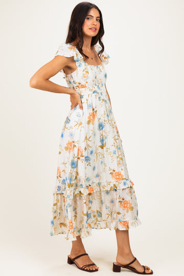 woman wearing a flowy white floral maxi dress with ruffle sleeves and a tiered skirt