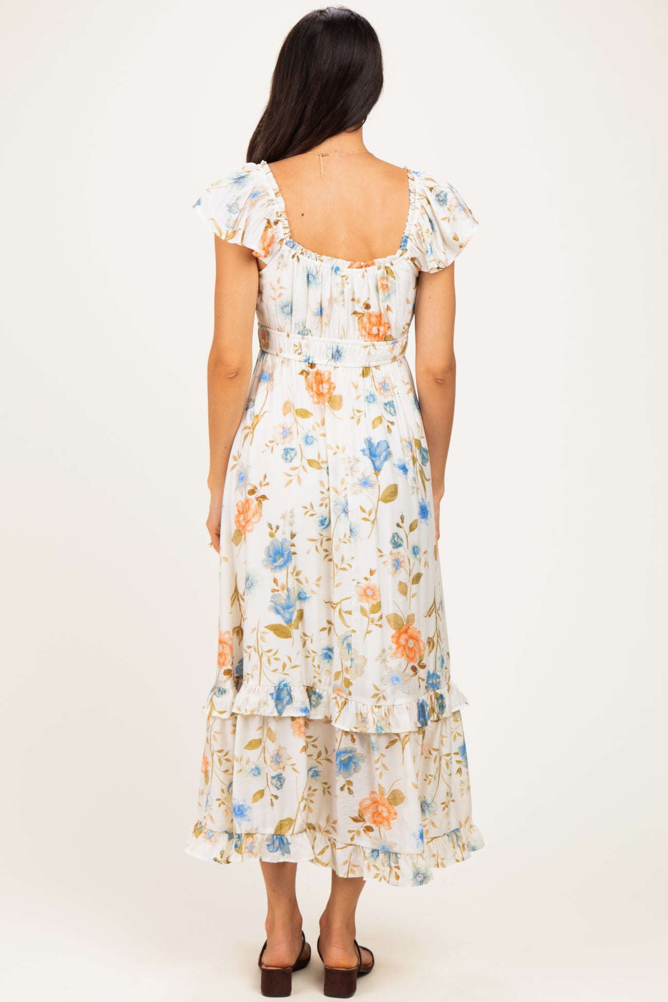 woman wearing a white floral tiered maxi dress with ruffled sleeves, shown from the back