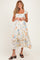 woman wearing a floral print maternity dress with ruffled sleeves and hemline, smiling against a neutral background