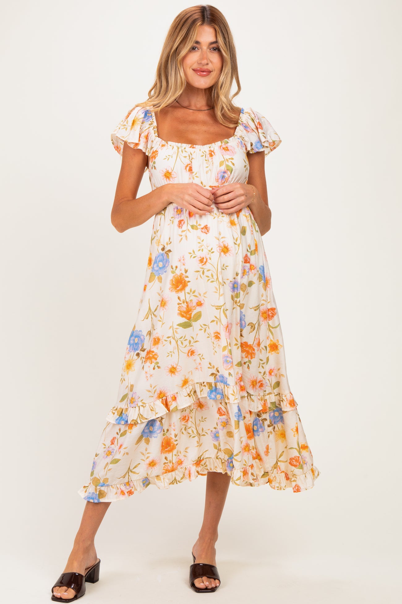 woman wearing a floral maternity dress with a square neckline and ruffled sleeves, showcasing her baby bump
