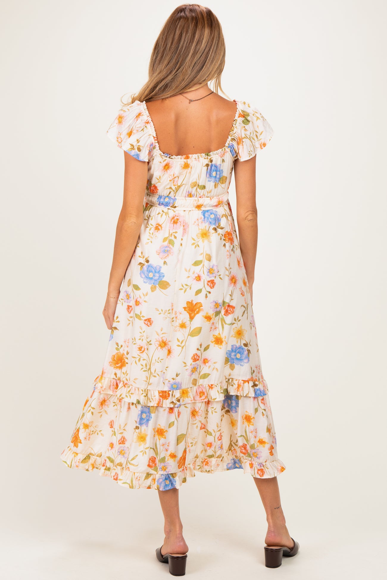 woman wearing a floral maternity maxi dress with ruffled sleeves and tiers, showing her baby bump from the back