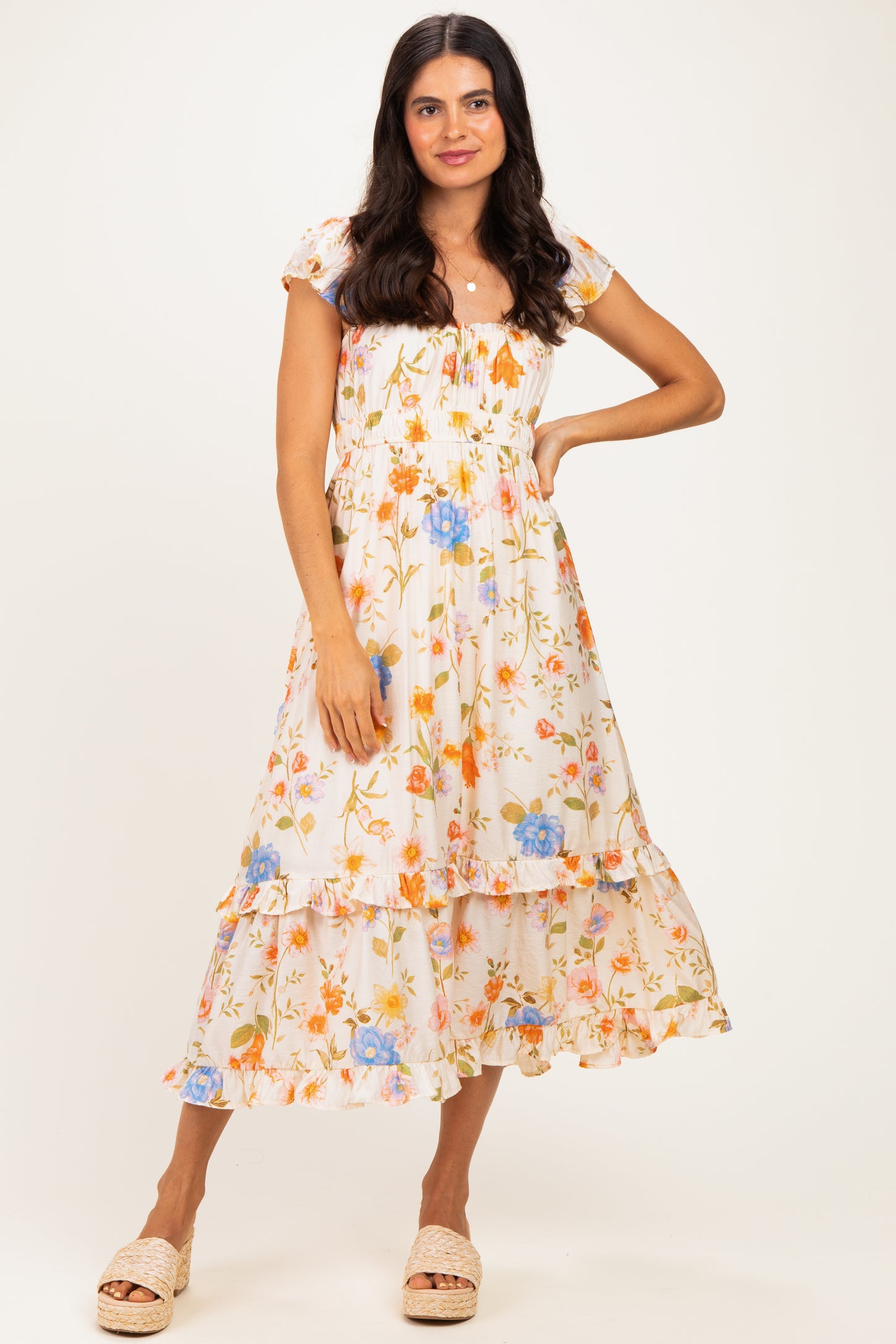 woman wearing a white floral midi dress with puff sleeves and tiered ruffles