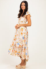 woman wearing a white floral midi dress with ruffle details and cap sleeves, styled with wedge sandals