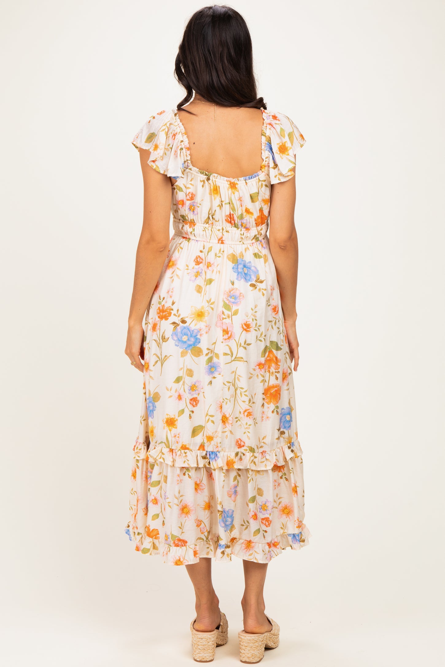 woman wearing a floral midi dress with ruffled sleeves and a tiered skirt, view from the back