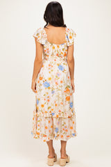 woman wearing a floral midi dress with ruffled sleeves and a tiered skirt, view from the back