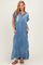 woman wearing a light blue denim maxi shirt dress with short sleeves and pockets, featuring a button-down front and a frayed hem