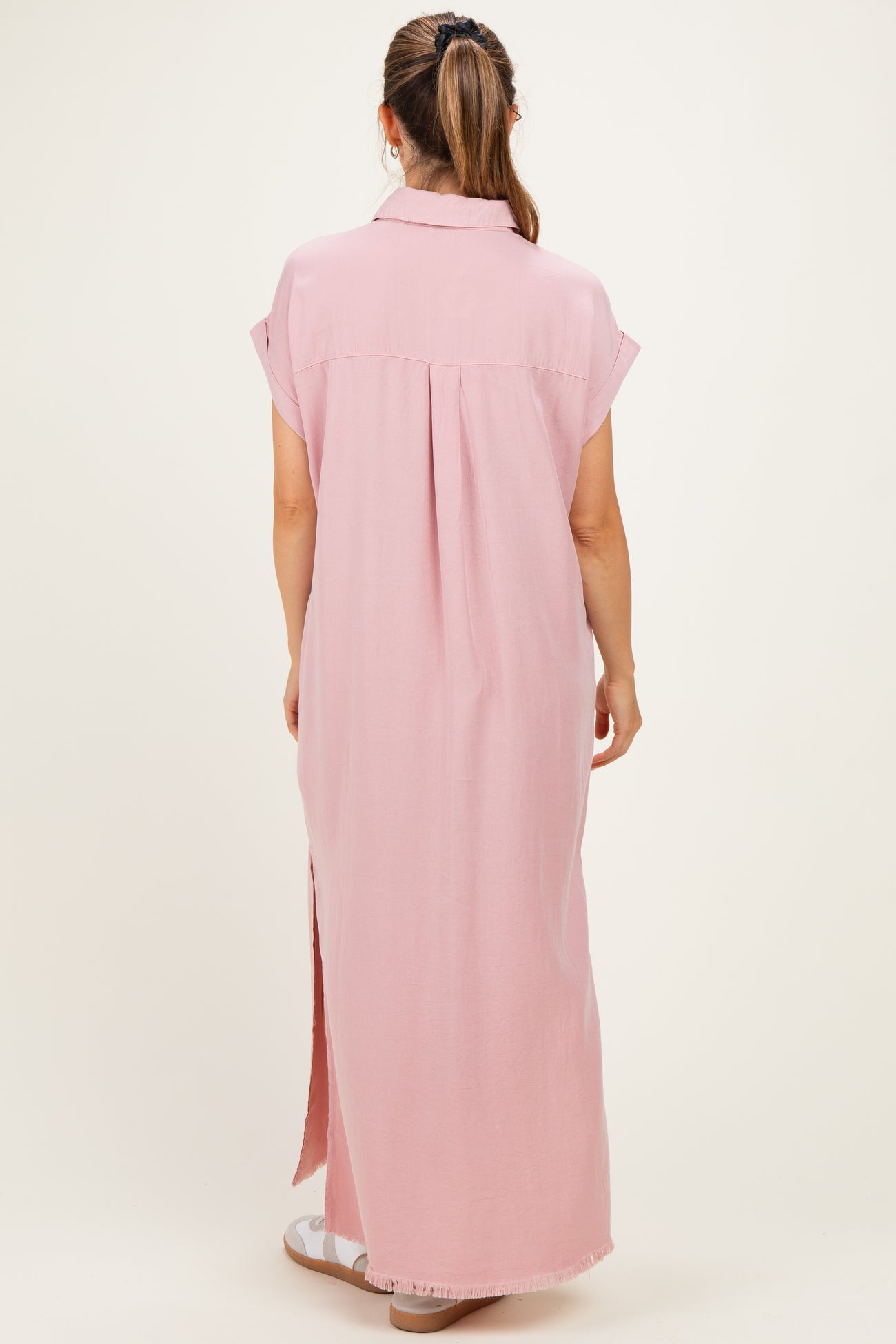 woman wearing a pink maxi maternity dress with short sleeves and a back pleat, showing a relaxed fit