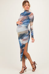 woman wearing a multicolored long sleeve maternity dress with side slits and holding her baby bump