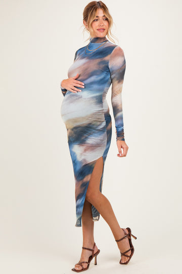 woman wearing a multicolored long sleeve maternity dress with side slits and holding her baby bump