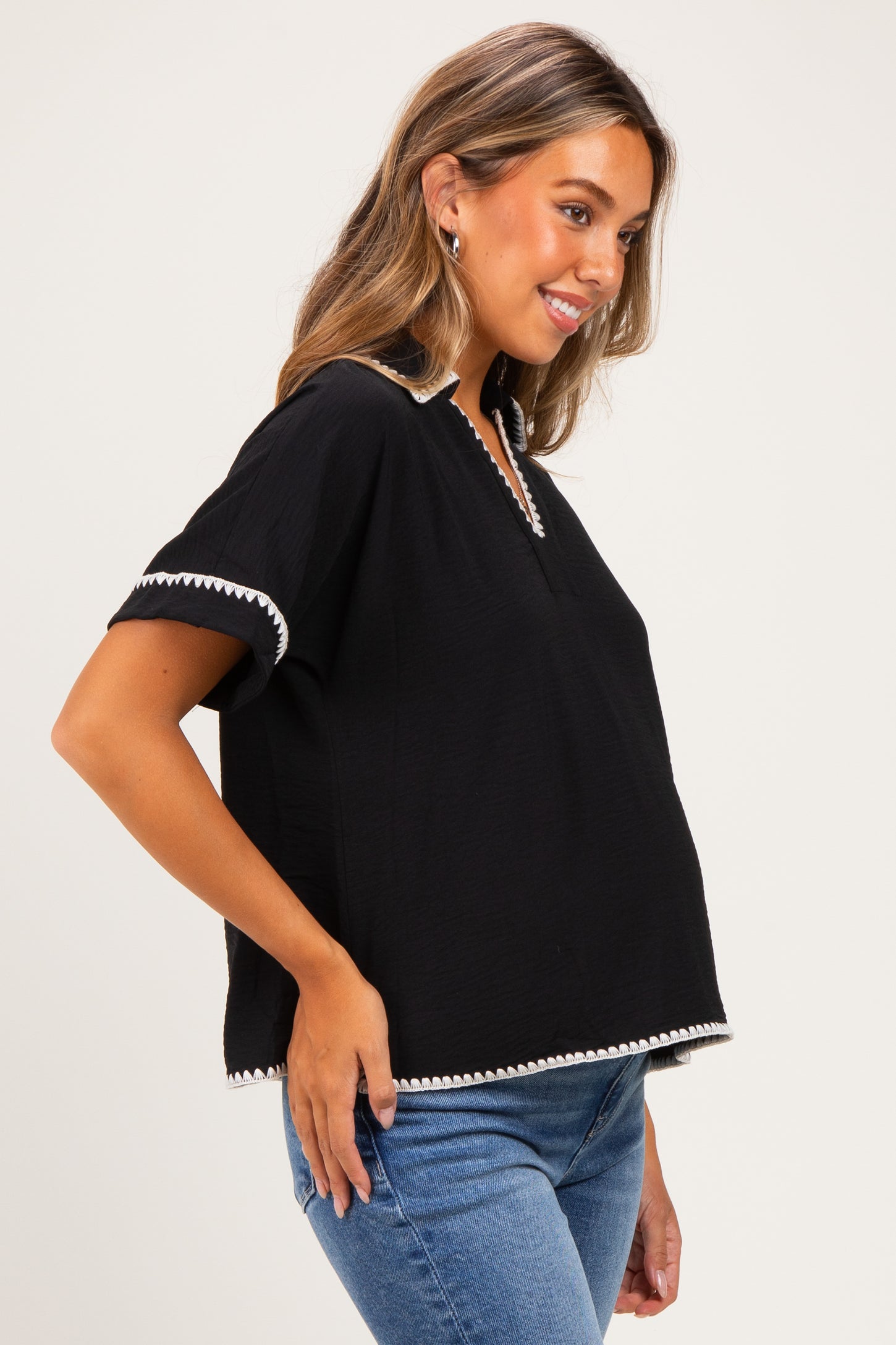 woman wearing a black maternity top with white trim and short sleeves, showing her baby bump