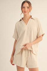 woman wearing a beige short sleeve top with a v-neck and matching shorts, relaxed fit and subtle texture