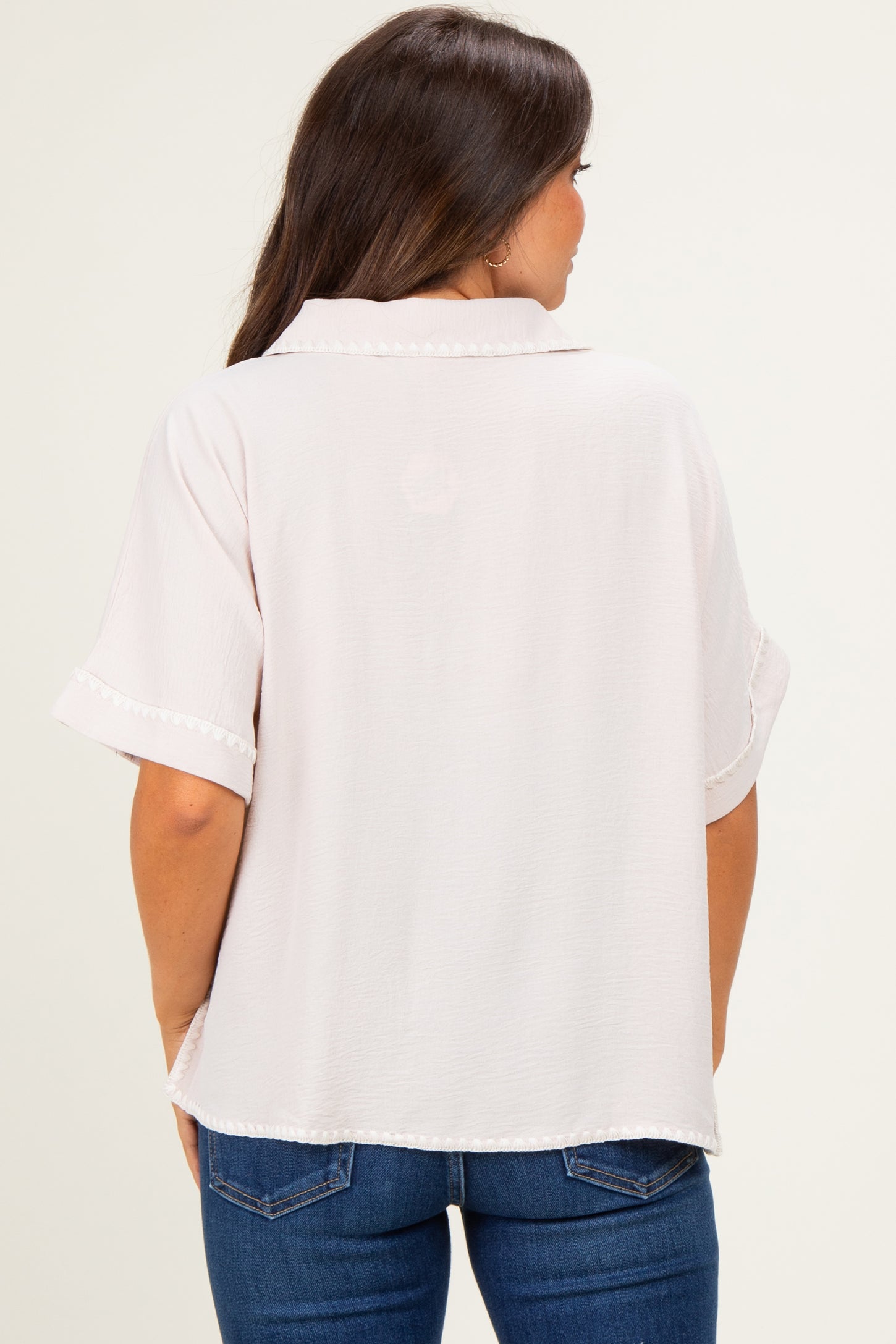 woman wearing a light pink maternity top with short sleeves and a relaxed fit, viewed from the back