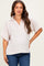 woman wearing a light pink maternity top with a collared neckline and short sleeves, showcasing a relaxed fit