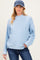 woman wearing a light blue cable knit maternity sweater with long sleeves and dark jeans