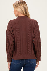 woman wearing a brown cable knit maternity sweater with a relaxed fit, viewed from the back