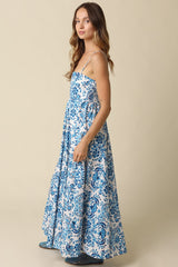 woman wearing a floral blue and white maxi dress with thin straps and a tiered skirt