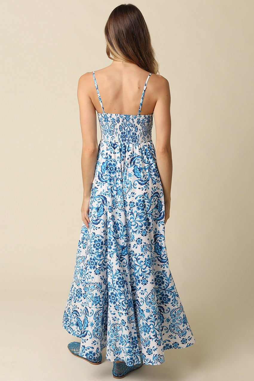 back view of a woman wearing a blue and white floral maxi dress with adjustable spaghetti straps