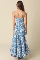 back view of a woman wearing a blue and white floral maxi dress with adjustable spaghetti straps