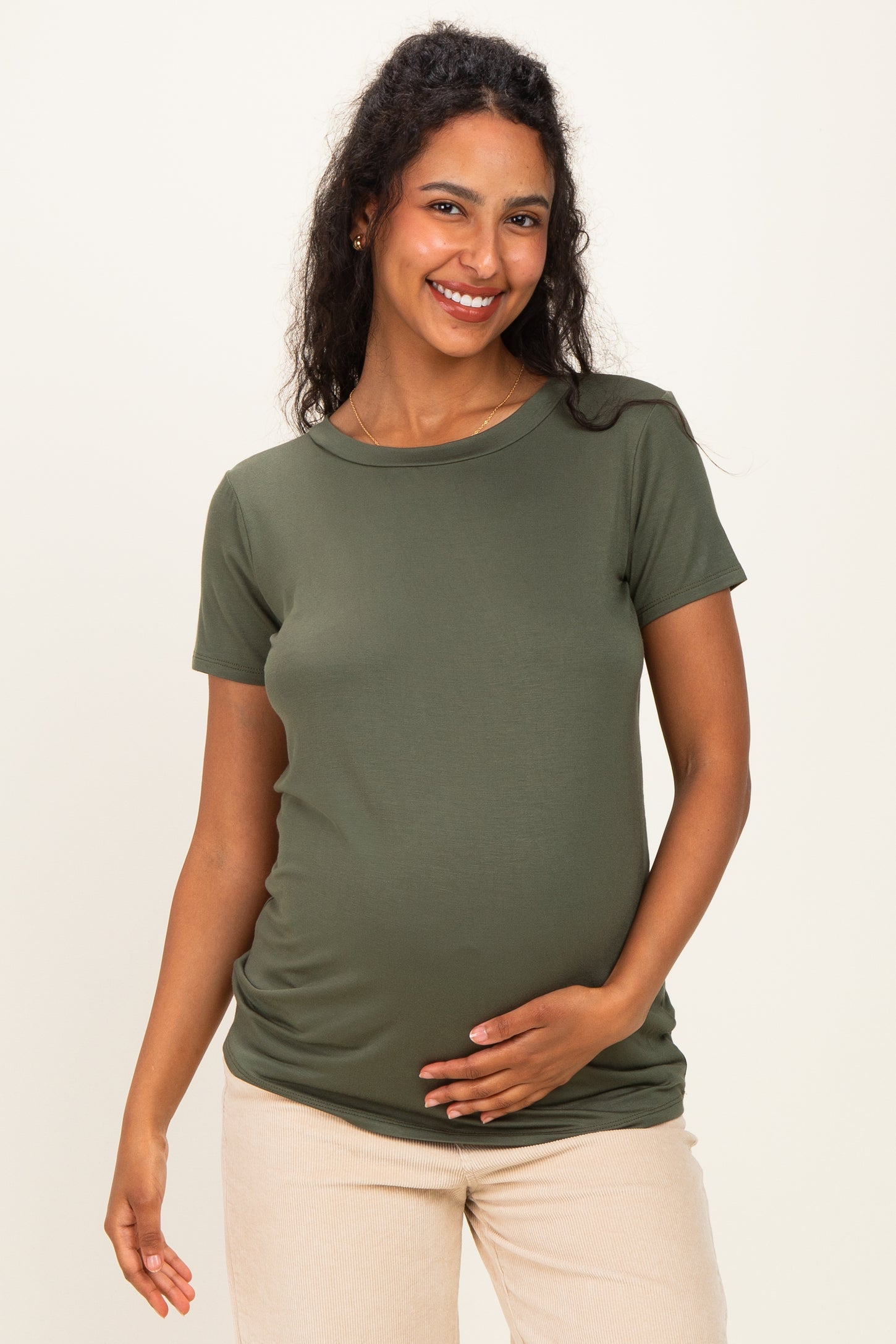 woman wearing a dark green short sleeve maternity top and holding her baby bump