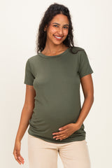 woman wearing a dark green short sleeve maternity top and holding her baby bump