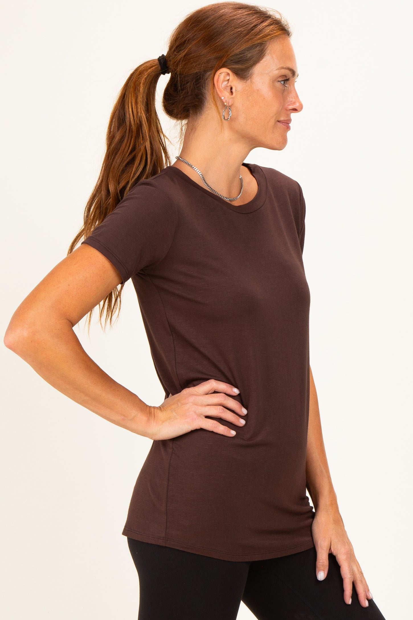 woman wearing a brown short sleeve top with a relaxed fit and side profile pose