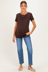 woman wearing a brown short sleeve maternity top and blue jeans, showing a visible baby bump