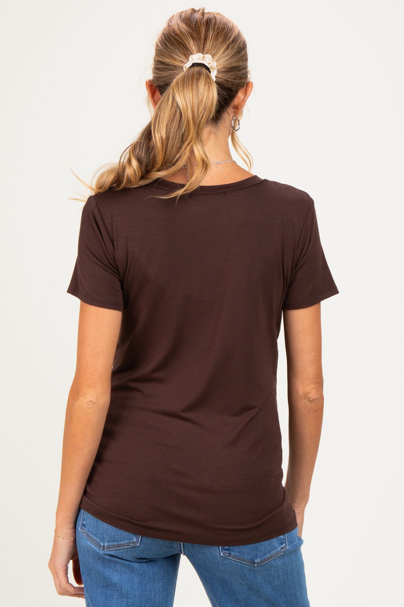 woman wearing a brown short sleeve maternity top, viewed from the back, with her hair tied in a ponytail