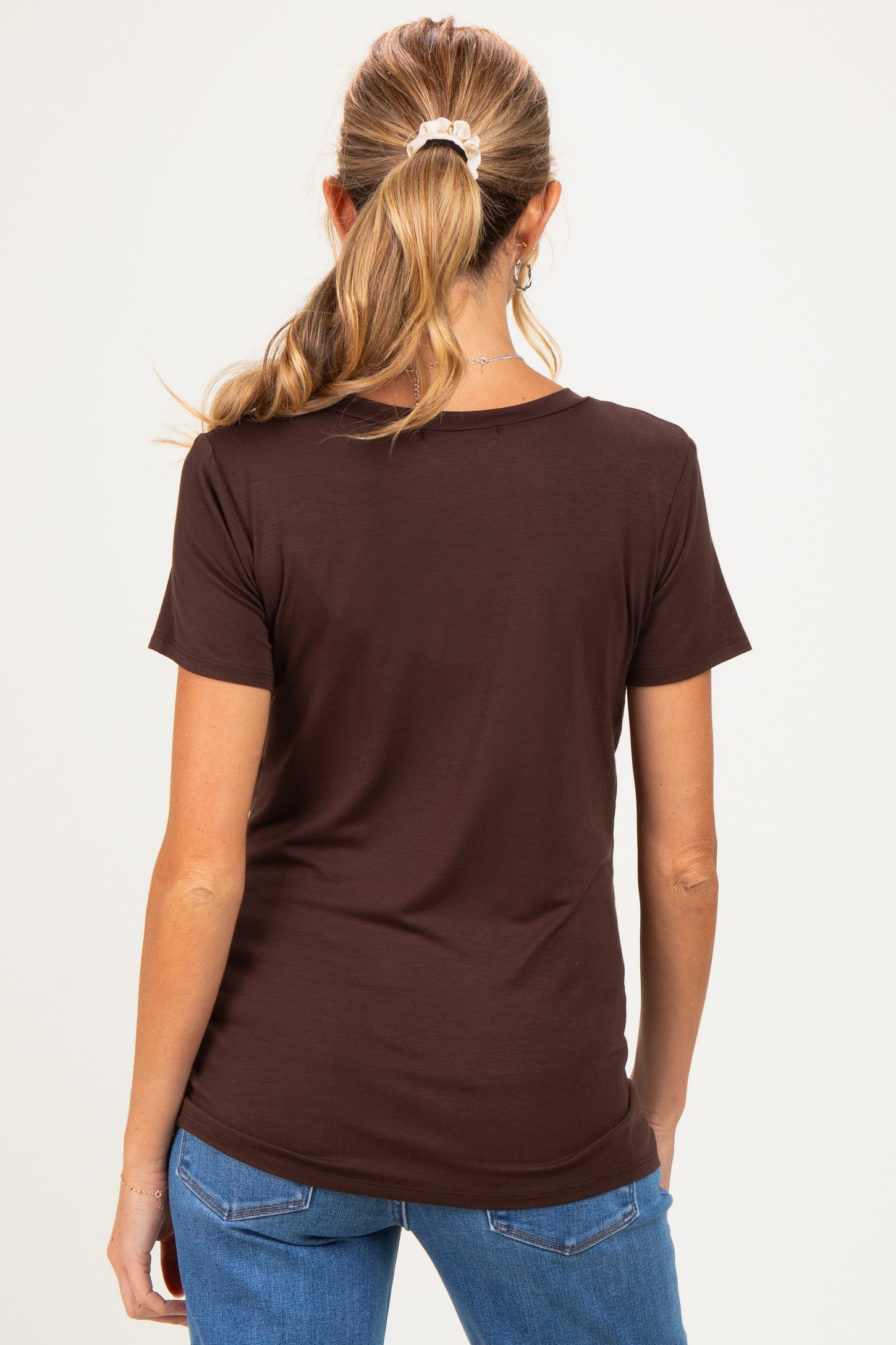 woman wearing a brown short sleeve maternity top, viewed from the back, with her hair tied in a ponytail