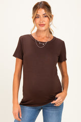 woman wearing a brown short sleeve maternity top and fitted jeans with a slight baby bump visible