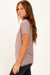 woman wearing a taupe short sleeve top and black jeans, standing sideways with a relaxed fit