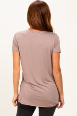 woman wearing a light taupe short sleeve top viewed from the back, featuring a relaxed fit and slightly longer hemline