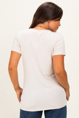 woman wearing a light beige short sleeve maternity top, shown from the back