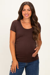 woman wearing a brown short sleeve maternity top and holding her baby bump