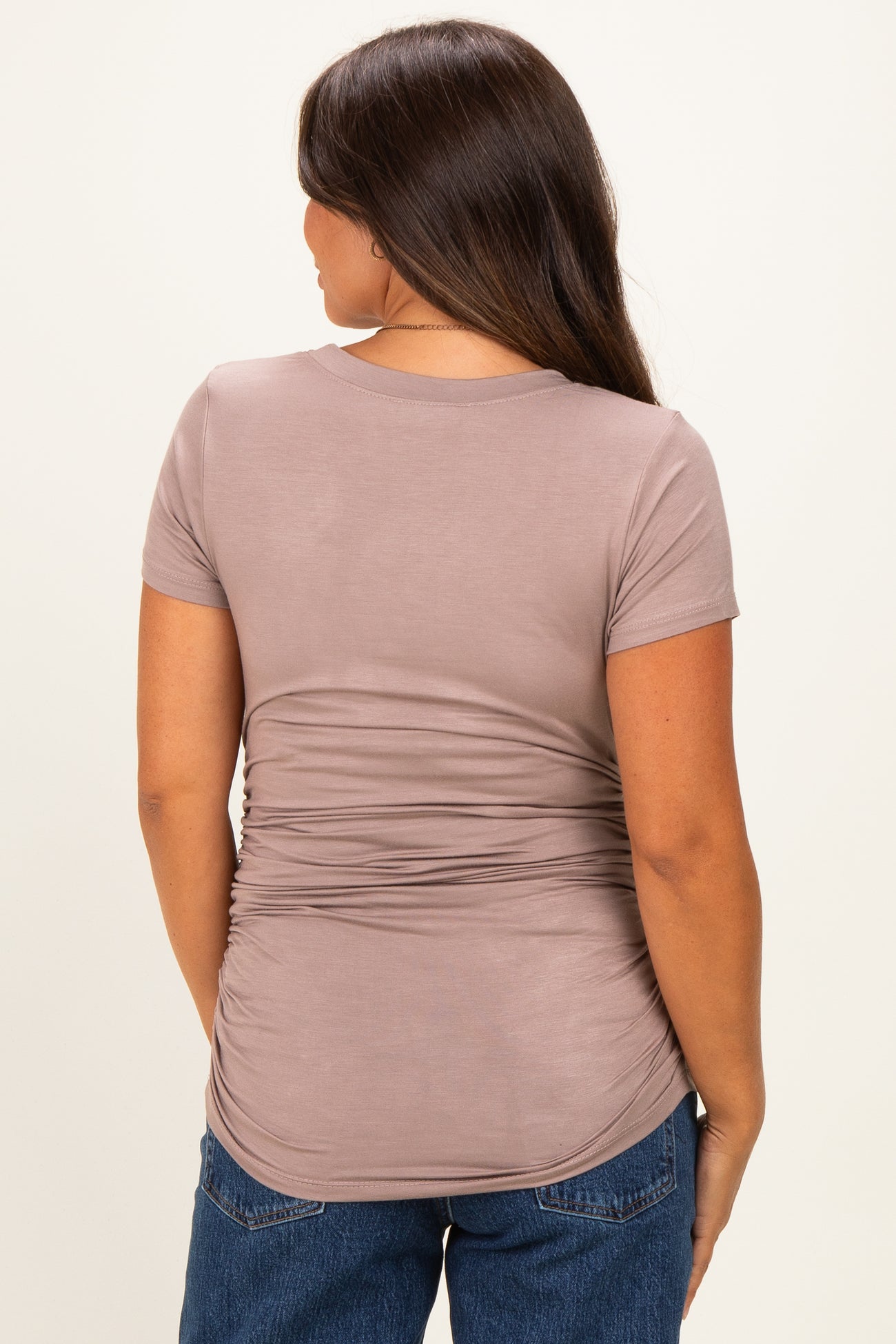 woman wearing a brown short sleeve maternity top with gathered side details, showing a baby bump from the back