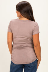 woman wearing a brown short sleeve maternity top with gathered side details, showing a baby bump from the back