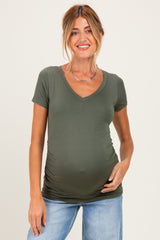 woman wearing a green short sleeve maternity top with ruching and showing her baby bump