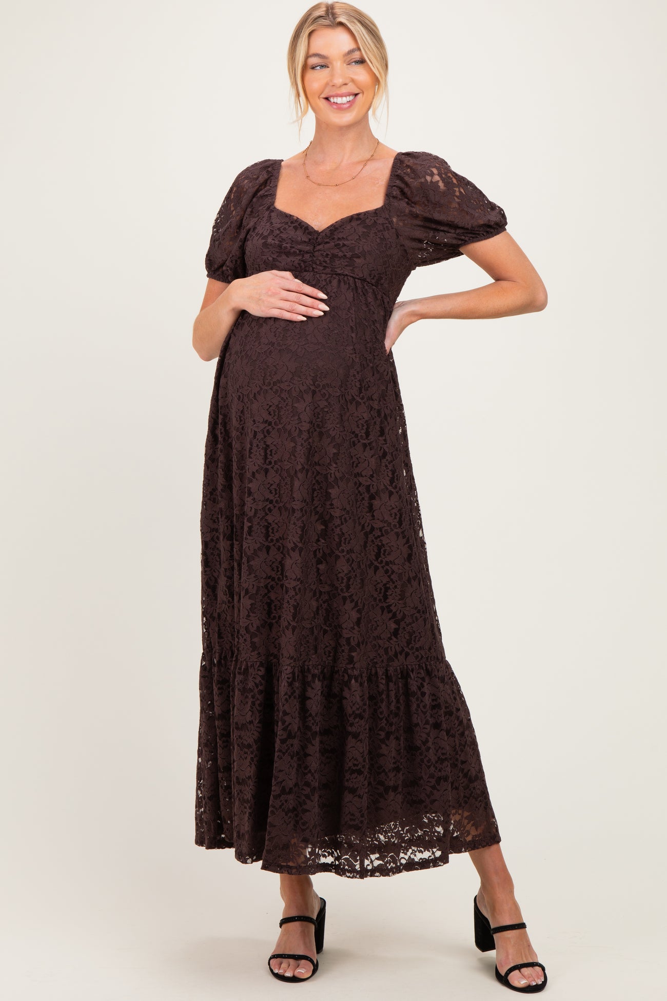 woman wearing a brown lace maternity maxi dress with puff sleeves and a baby bump