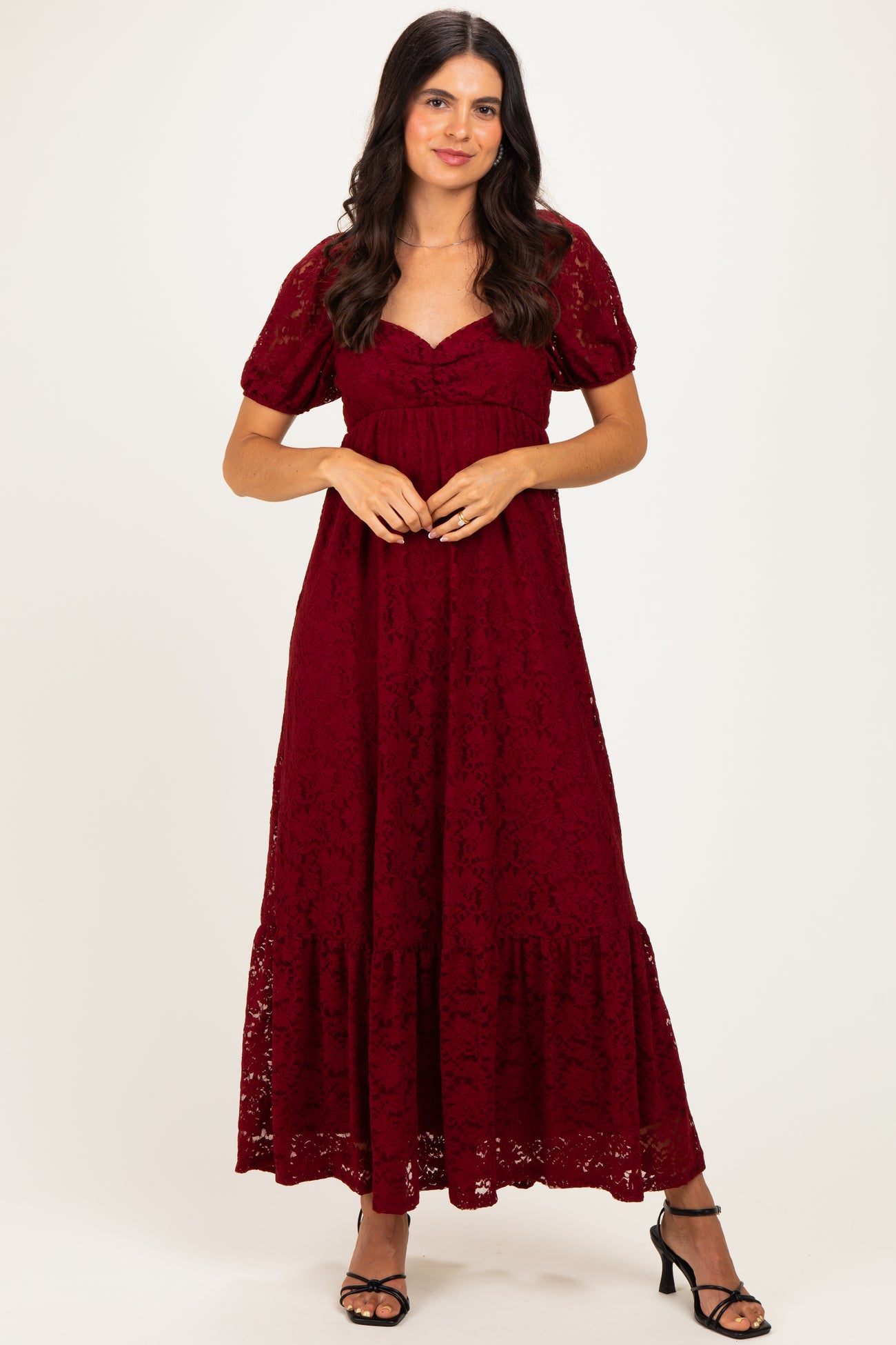 woman wearing a burgundy lace maxi dress with short sleeves and a tiered hem, standing in a neutral background