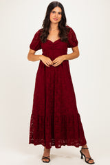 woman wearing a burgundy lace maxi dress with short sleeves and a tiered hem, standing in a neutral background