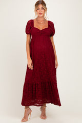 woman wearing a burgundy lace maternity maxi dress with puff sleeves and a gathered bodice, showing her baby bump