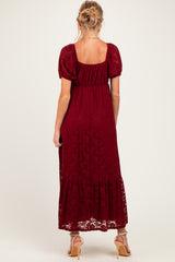 woman wearing a burgundy lace maternity maxi dress with short puff sleeves and a ruffled hem